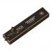 A stack of glossy dark-brown wrappers with gold trim shows macadamia nuts and honey illustrations. One bar sits unwrapped and sliced, revealing dense amber nougat studded with whole macadamias and enrobed in glossy dark chocolate that gleams under soft light.