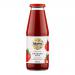 A clear glass jar of smooth, vibrant red tomato purée stands upright on a neutral background. A white-and-green label wraps the jar, showing the Biona logo and botanical illustrations of tomatoes and leaves. A ridged metal screw lid seals the top.