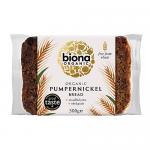 Dark, dense pumpernickel loaf sits sliced, revealing a tight, moist crumb with fine, evenly distributed air pockets. Crust is deep brown and slightly glossy, edges firm. Surface shows subtle rye grain texture and a rustic, hearty appearance.