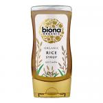 A squat glass jar holds glossy amber rice syrup that gleams under light. A white label encircles the jar, showing the green Biona logo and the product name in clear typography. A metallic screw lid and smooth glass give a simple, natural presentation.