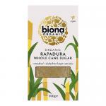 Five 500g Biona Organic Rapadura wholecane sugar packs stand side by side. Each pack shows natural brown tone and minimalist label with green Biona logo and product name. Crinkled paper pouches suggest rustic, unrefined sugar in uniform retail packaging. On a plain white surface with subtle shadows.