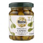 A clear glass jar with a green screw cap and a white Biona Organic label stands filled with small olive-green capers suspended in brine. Several identical jars are arranged together on a pale background, lit to show texture and glossy reflections.