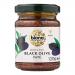 A clear glass jar with a black metal lid reveals smooth, dark-brown olive pate. The white label features a green Biona logo, a small black olive illustration, bold product name and fine ingredient text. Six identical jars sit grouped in two rows on a plain white background. Subtle glass highlights.