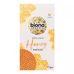 Bright rectangular box displays the Biona Organic logo and green accents. A stack of golden honey-coated waffles sits in the foreground with a glossy honey drip and honeycomb motifs. Organic certificate marks and ingredient illustrations appear on a clean white background. Soft shadow beneath edges.