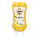 Six translucent plastic squeezy bottles of Biona organic mustard sit in a neat pack. Bright yellow sauce shows through each bottle; white labels feature the green Biona logo, ingredient text and mustard imagery. Soft studio light casts subtle shadows on a plain white background. in a kraft tray with