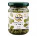 A cluster of six clear glass jars of Biona Organic capers in pale wine vinegar sits on a neutral surface. Small green capers float in golden brine, visible through transparent jars. White labels show the green Biona logo and product name; metal screw lids top each jar. Warm highlights catch the jars
