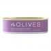 A glossy glass jar of deep purple Kalamata olives sits against a neutral background. The Babylonstoren label wraps around the jar, showing clean typography and subtle olive-branch imagery. Brine glints on the fruit, and a metal lid reflects soft studio lighting. A simple wooden spoon lies beside them.