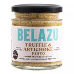 A clear glass jar with a metallic lid holds a creamy olive-green pesto speckled with darker truffle flecks and small artichoke pieces. A cream-and-black label displays the Belazu branding and product name; soft light reflects off the jar against a neutral background. Subtle sheen highlights texture.