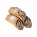 An open box reveals six golden-brown cannoli, each crisp shell piped with creamy salted-caramel filling that slightly oozes from the ends. A light dusting of powdered sugar flecks the shells while tiny caramel shards and glossy drips catch the light. The tray rests on rustic wood with crinkled paper