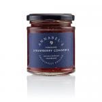 Six small glass jars sit aligned, filled with glossy deep-red strawberry conserve. Each jar wears a cream lid and a vintage-style label reading Annabel's Yorkshire Strawberry Conserve, featuring delicate botanical illustrations and gold trim on a warm cream backdrop.
