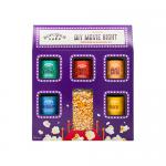 Bright, stacked tins and sachets display six labeled seasoning varieties beside a glass jar of golden popped corn. Colorful powder spills, wooden scoop rests on a linen cloth, and the kit’s minimal branding and clean typography sit against a neutral background, highlighting textures. Soft contrasts.