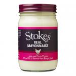 A clear glass jar of mayonnaise sits on a neutral background. Creamy white mayo fills the jar, visible through the glass. A paper label wraps the jar with bold brand lettering and subtle color accents. A metal lid crowns the jar, and soft lighting highlights the glossy texture. A soft shadow falls.