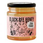 Six clear glass jars of amber Starflower honey sit in a tidy row. Each jar displays a black label with a stylized bee and starflower illustration, a gold rimmed lid, and the viscous honey inside catching soft studio light.