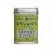 A photo shows six clear glass jars of Dylan’s Secret Seasoning, each with a black screw cap and a white label bearing the brand name and herb illustrations. Warm reddish-brown spice fills the jars, which are neatly arranged on a plain cardboard tray.