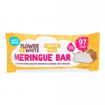 A glossy white meringue bar shines with pale caramel-gold sheen, topped with delicate piped flowers in white and metallic gold. Swirled textures and tiny sugar pearls catch the light; the compact bar sits on a neutral surface, its edges crisp and airy.