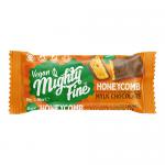 A single Mighty Fine Vegan Salted Caramel Mylk chocolate bar sits angled on a pale surface. Bright turquoise and cream wrapper displays bold brand lettering, caramel-drip illustration and vegan icon. Glossy film catches light, casting soft shadow and emphasizing texture.