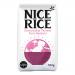 A photo shows a cardboard tray holding twelve 500g bags of Nice Rice Pure Basmati, arranged in three rows. Each bag displays the Nice Rice logo and a 'Pure Basmati' label on green-and-white packaging with a clear window revealing long white grains. The scene has soft studio light on a pale backdrop.