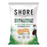 Twelve 80g Shore Seaweed Chips packets are arranged in a neat grid, each packet displaying deep blue and sea-green artwork, with dark green seaweed chips visible through a small clear window, a prominent 'Salt & Balsamic' label and simple Shore branding. Soft natural light highlights textures. Close