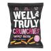 A group of ten 30g Well&Truly Crunchies Smokey Bacon snack packs sits in a tidy pile. Each pack displays the Well&Truly logo, smoky red-brown packaging and a stylized bacon image; a few opened packs reveal irregular, crunchy bacon-flavored pieces.