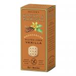 A clean, rectangular packet of six round, golden-brown biscuits sits on a neutral surface. The wrapper displays simple bakery branding and Madagascan vanilla text. Biscuits show delicate sugar-sprinkle tops and a crisp, slightly cracked surface revealing a tender, crumbly interior. Soft light falls.