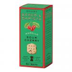 A bright rectangular box displays six artisan round biscuits in two rows. Each biscuit is golden-brown with a glossy dark-red Morello cherry jam centre and a light sugar dusting. A rustic bakery logo and simple white packaging complete the image. Crumbly edges and visible oat grains hint at handwork