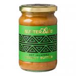 Six glossy glass jars stand in a row, each labeled with a bold, vintage-style Butter Bike logo and fiery jalapeño graphics. Reddish-brown peanut butter peeks through the glass. Bright green cap tops and scattered jalapeño slices and peanuts frame the scene Soft studio lighting casts warm highlights