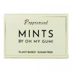 A small rectangular 18g pack of OH MY GUM! mints sits on a neutral surface. A bold OH MY GUM! logo dominates the glossy, brightly colored wrapper. Several smooth white mint tablets spill from the open pack, their rounded surfaces catching soft highlights. Nearby mint leaves and tiny water droplets..