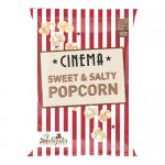 A neat cluster of twelve 90g bags of Joe & Seph’s Cinema Sweet & Salty Popcorn sits on a pale tabletop. Golden, glossy kernels and sugar shards spill from a ripped bag. Black packaging with gold lettering and a cinema-style label frames the crunchy pile.