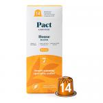 A stack of Pact House Blend coffee pod boxes sits on a grocery shelf, each rectangular box showing rustic brown and cream packaging with a stylized coffee bean logo. Individual pods peek from an open box. Price tags and surrounding items blur into the aisle background. Soft overhead lighting glows.