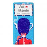 A vibrant wrapped chocolate bar sits half-unwrapped, revealing glossy milk chocolate with neat square segments and a ribbon of salted caramel seeping between them. The wrapper shows a stylized London guard in a red tunic with tricolor accents and playful graphics.