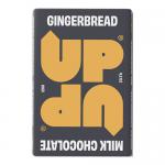 A neat arrangement shows a stack of gingerbread milk cookies in a 120g pouch beside ten individually wrapped UP-UP chocolate pieces. Bright, glossy wrappers display warm brown and cream tones, with crisp edges, visible textures, and playful branding on each pack. Soft crumbs catch warm studio light.