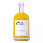 Six 500ml Jinger bottles stand in a cardboard carrier, each filled with warm amber liquid. Labels show ginger and turmeric illustrations. Festive red and green packaging features holly and snowflake motifs. Bottles sit on a wooden table with scattered ginger roots and cinnamon sticks. Soft warm glow.