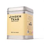 A festive box of Jinger Drinks ginger lemons and limes tea bags sits on a wooden table. Bright citrus illustrations in yellow and green surround a steaming cup, scattered tea bags and cinnamon sticks, while twinkling Christmas lights and pine sprigs add a cozy holiday glow. Starry snowflakes border.