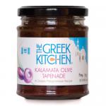 A clear glass jar of The Greek Kitchen Kalamata olive tapenade (180g) sits upright, revealing deep purple-black, coarse olive paste. The label shows the brand and product name; a silver lid caps the jar against a plain background.