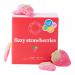 A colorful rectangular box shows ten bright red, sugar-coated strawberry candies nestled in a clear tray. Packaging features playful hand-drawn family illustrations, bold pink and green lettering that reads the brand and product name, and fizzy sparkles graphics across a white background. soft focus