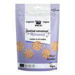 Kookie Cat Salted Caramel Almond mini cookies sit in a clear-front bag showing golden-brown, bite-sized rounds studded with chopped almonds and glossy caramel swirls. Light salt crystals sparkle on the surface, and a playful Kookie Cat logo tops quaint bakery-style labeling.