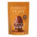 A glossy box of Forest Feast Salted Caramel Milk Chocolate Dates sits against a soft neutral background. The packaging shows the brand logo, an image of chocolate-coated dates with caramel drizzle, weight and '6' pack indication, plus leafy design accents. Soft lighting and a shallow depth of field.