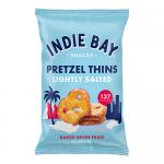 A cluster of small Indie Bay Pretzel Thins packs sits on a light surface. Thin, golden-brown pretzels peek through partially transparent bags bearing the Indie Bay logo. Crisp, ring-shaped pretzels form neat stacks inside each compact 35g pack. Soft shadows and pale blue backdrop highlight textures.