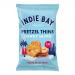 A cluster of small Indie Bay Pretzel Thins packs sits on a light surface. Thin, golden-brown pretzels peek through partially transparent bags bearing the Indie Bay logo. Crisp, ring-shaped pretzels form neat stacks inside each compact 35g pack. Soft shadows and pale blue backdrop highlight textures.