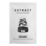 A matte black 250g coffee bag stands upright against a neutral backdrop. A bold white Extract Coffee Roasters logo tops a minimalist label stating Organic Espresso Beans. A small organic seal appears near the base. Glossy brown beans spill beside the bag, casting soft shadows. With soft reflections.