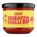 Glossy scarlet chilli dip sits in a clear plastic tub; its smooth surface shows darker red swirls and tiny flecks of chilli. A bright, modern label wraps the side with bold white type and simple graphics. The lid reflects soft overhead light, adding a subtle highlight. A hint of gloss frames the rim.