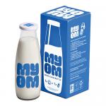 A tidy array of 24 clear glass milk bottles sits in neat rows, each 500 ml bottle showing a classic rounded shoulder, narrow neck and screw-top cap. Light catches smooth glass surfaces, creating soft reflections and shadows on the wooden tabletop beneath the uniform, cylindrical forms. With soft sheen