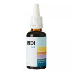 An amber 30ml dropper bottle labeled Indi Supplements Rest sits on a pale wooden surface. The white label shows teal and gray graphics and neat typography. Soft daylight glints on the glass; a blurred green plant and neutral backdrop form a calm, minimalist lifestyle scene. Subtle reflections glint.