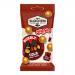 Photo shows a glossy candy pouch with the Van Slooten logo large at the top, warm brown and amber tones, illustrated cola bubbles and fizzy rings, scattered shiny, oval chewy candies at the foreground, clear window revealing treats and playful typography across the wrapper. Glossy sheen catches sun.