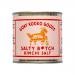 A small glass jar with a metal lid displays a bold label reading salty B*Tch, Goat Rodeo Goods and Kimchi Salt. The label mixes red, black and cream tones with distressed typography and chili graphics. Six identical jars sit aligned on a grocery shelf under soft lighting. small ink sketch of a goat.