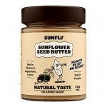 Six jars of Sunfly Sunflower Seed Butter sit in a neat group. Each clear jar shows creamy beige sunflower spread inside, topped by green lids and bright yellow labels featuring a sunflower graphic and text. A few sunflower seeds scatter across the white surface beneath.