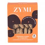 A bright package displays Zymi organic biscuits arranged beside cinnamon sticks, scattered sesame seeds and a sliced orange with a splash of juice. The biscuits show golden-brown edges and textured surfaces, and the brand logo appears prominently on the wrapper. Warm earthy tones and matte finishes.