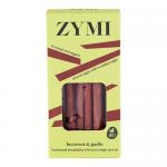 A clear-front packet shows slender, ridged breadsticks in warm pink and beige tones from beetroot swirls, speckled with garlic flecks. The sticks lie in an orderly bundle, their crisp texture and rustic, handcrafted surface visible through the transparent wrap and simple label. Soft sheen, crumbs...