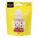 A colorful pouch of Sweet Lounge Vegan Fizzy Cola Bottles sits facing forward, its bright logo and vegan badge prominent. A clear window shows brown cola-shaped gummies coated in fizzy sugar crystals; studio lighting accentuates their glossy, slightly translucent texture. Soft shadow sits beneath it.