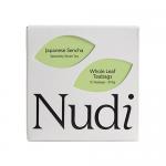 A rectangular green-and-white box sits front-facing, labeled Nuditea Japanese Sencha with Japanese characters and a plastic-free icon. Scattered bright green tea leaves and a single teabag with its string lie beside the box on a neutral surface, giving a simple, natural look.